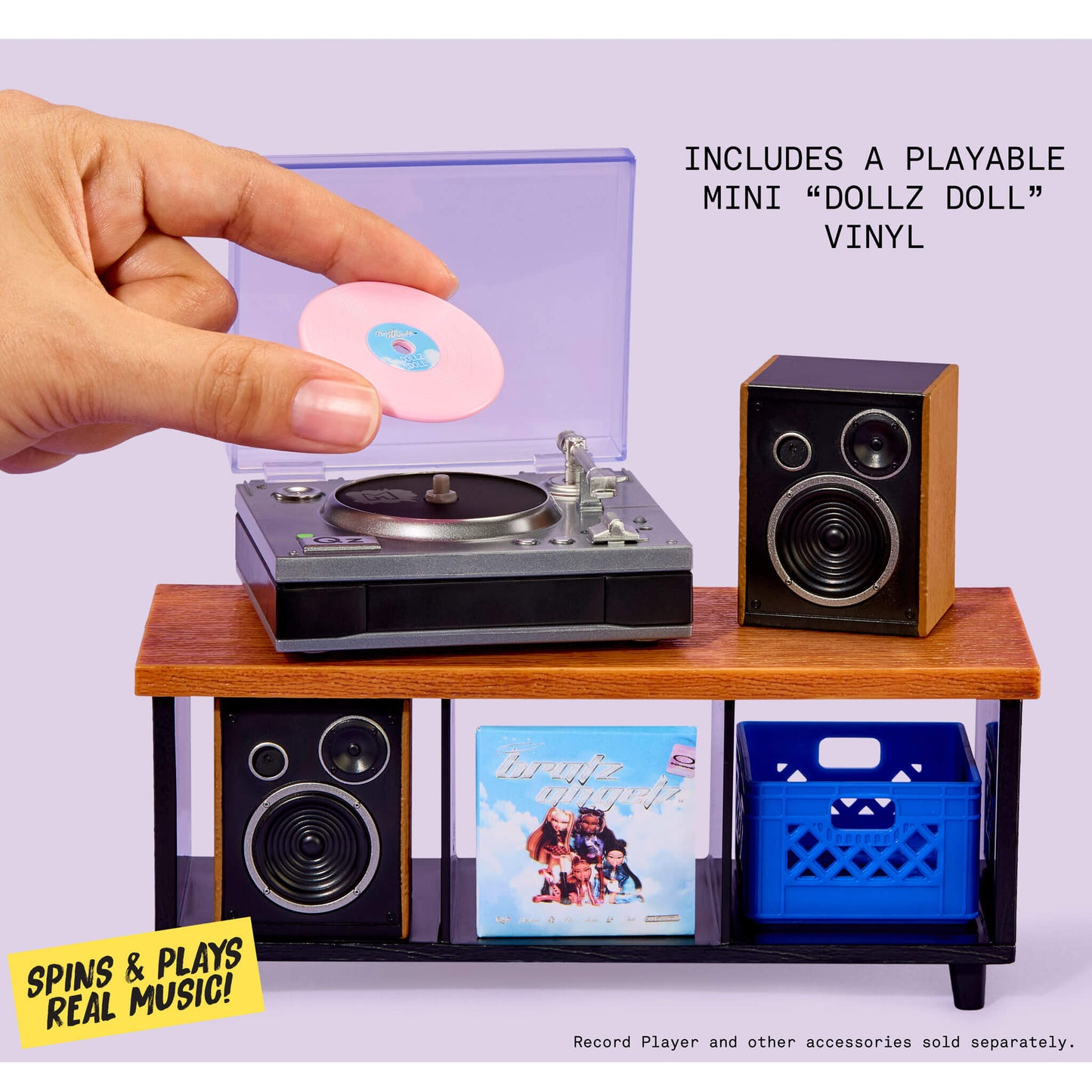 Miniature record player with a hand placing a vinyl record on it against a purple background with ‘Spins & Plays Real Music’ on left side.