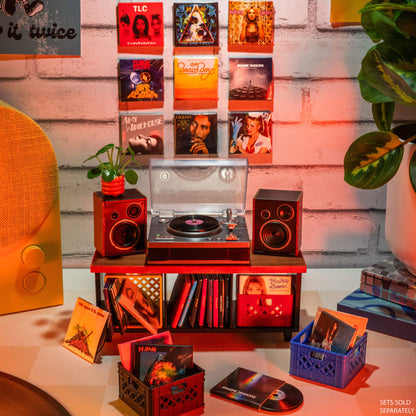 Mini record player setup with mini records and speakers on a wooden surface against a brick wall.