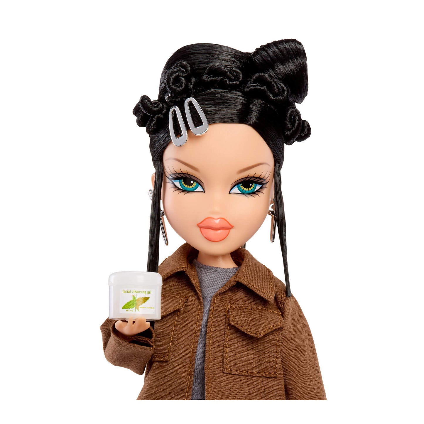 Toy doll with black hair styled in buns, wearing a brown jacket and holding a small white container.