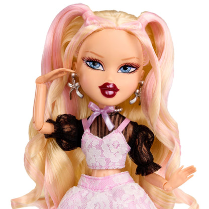 Doll up-close with blonde hair styled in pigtails, wearing a pink outfit 