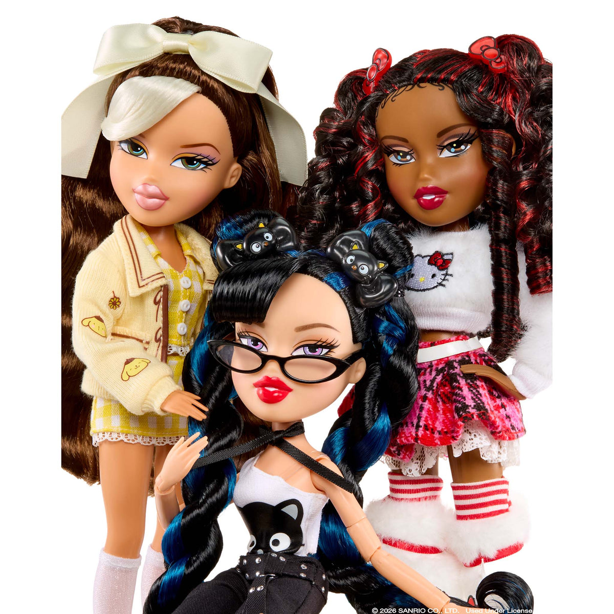 Three Bratz doll figures posed together against a plain white background. One doll has brown hair with a large cream bow, wearing a cream jacket and plaid skirt.